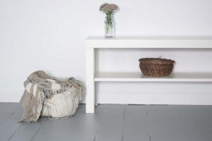 white table and shelf unit next to a basket holding cloth materials
